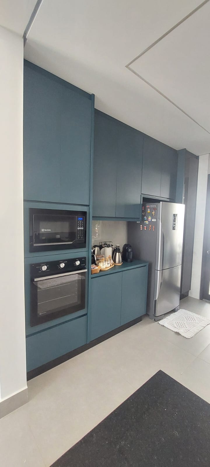 Cozinha azul petróleo com torre para forno e micro-ondas embutidos