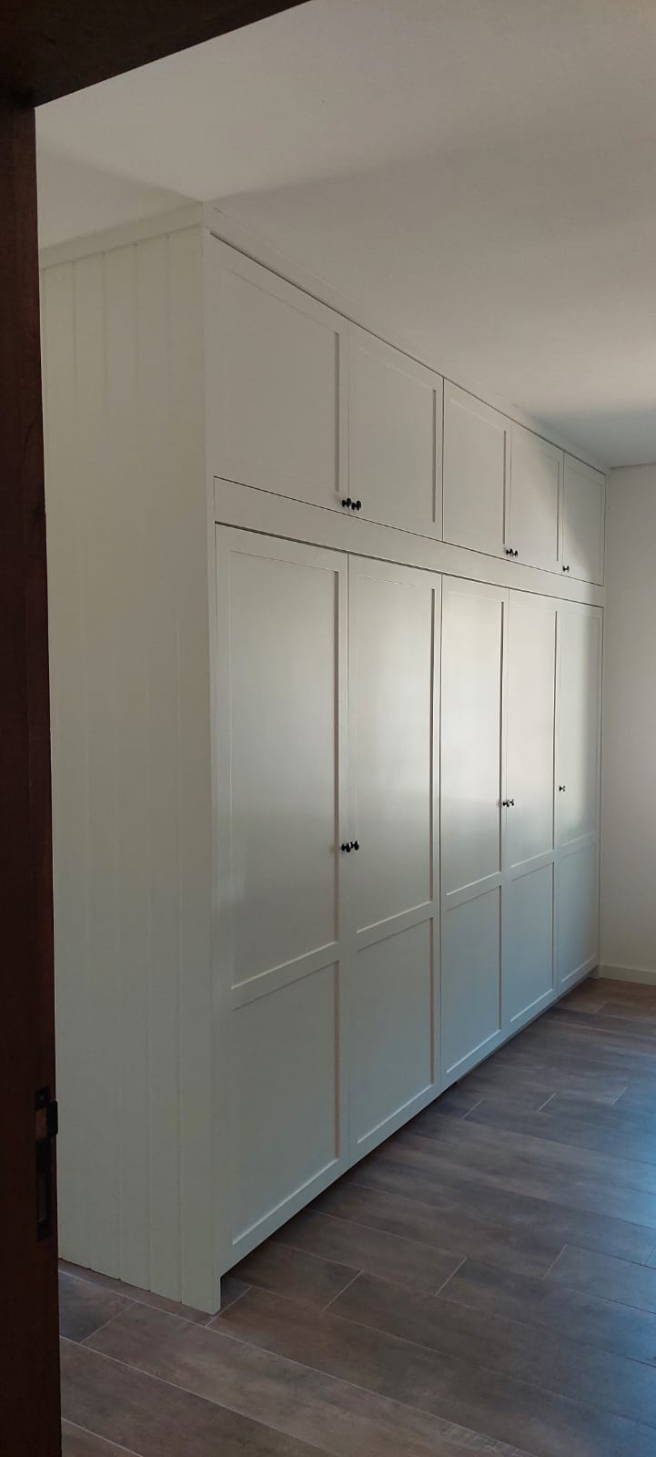 Armário branco estilo shaker do piso ao teto com maleiros