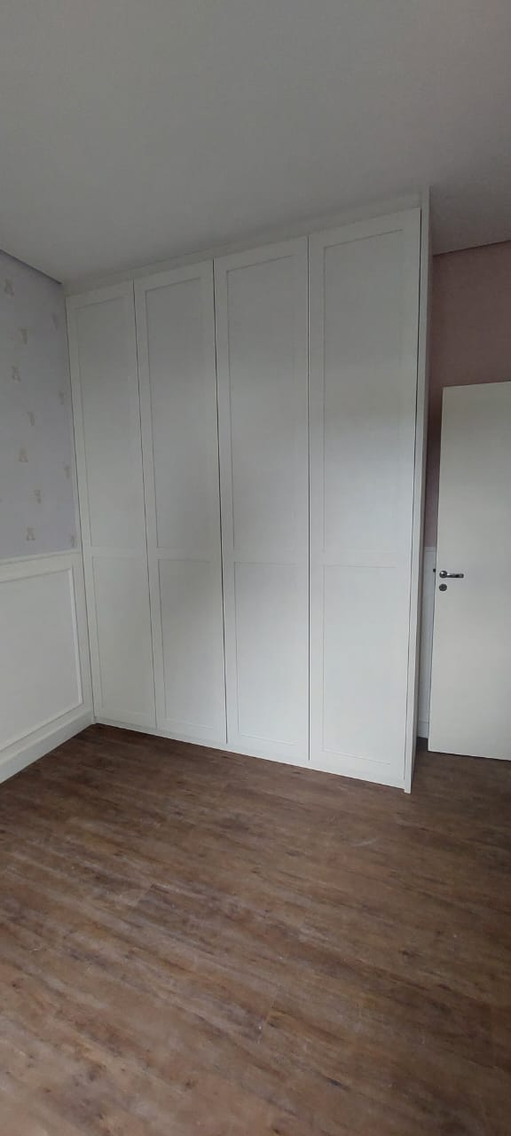 Quarto infantil com armário branco estilo shaker e papel de parede lilás