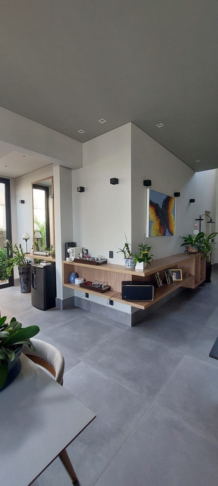 Aparador suspenso de madeira com canto café, plantas e quadro colorido