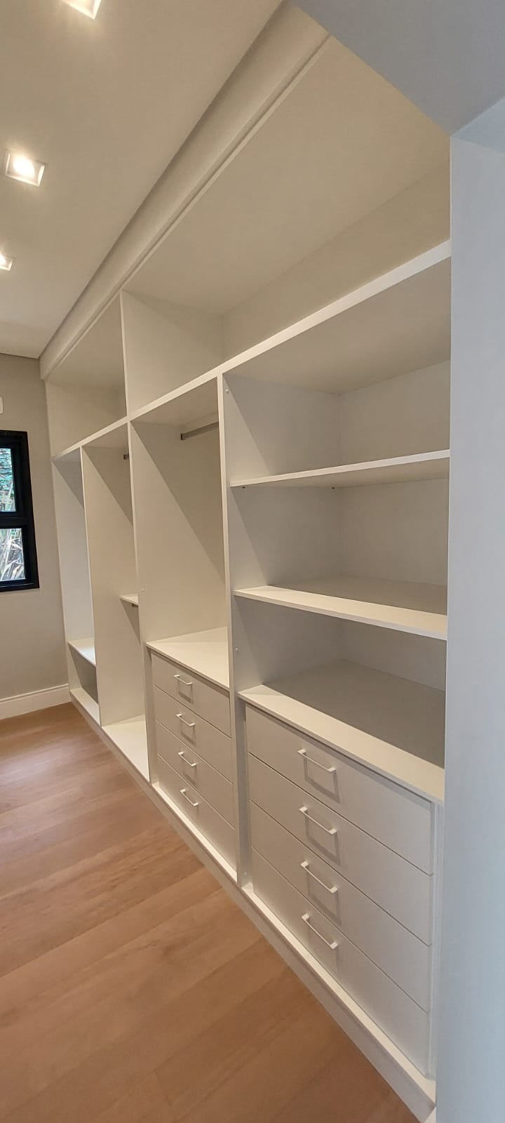Closet planejado com prateleiras, cabideiros e gaveteiros do projeto de Eduardo Tavares