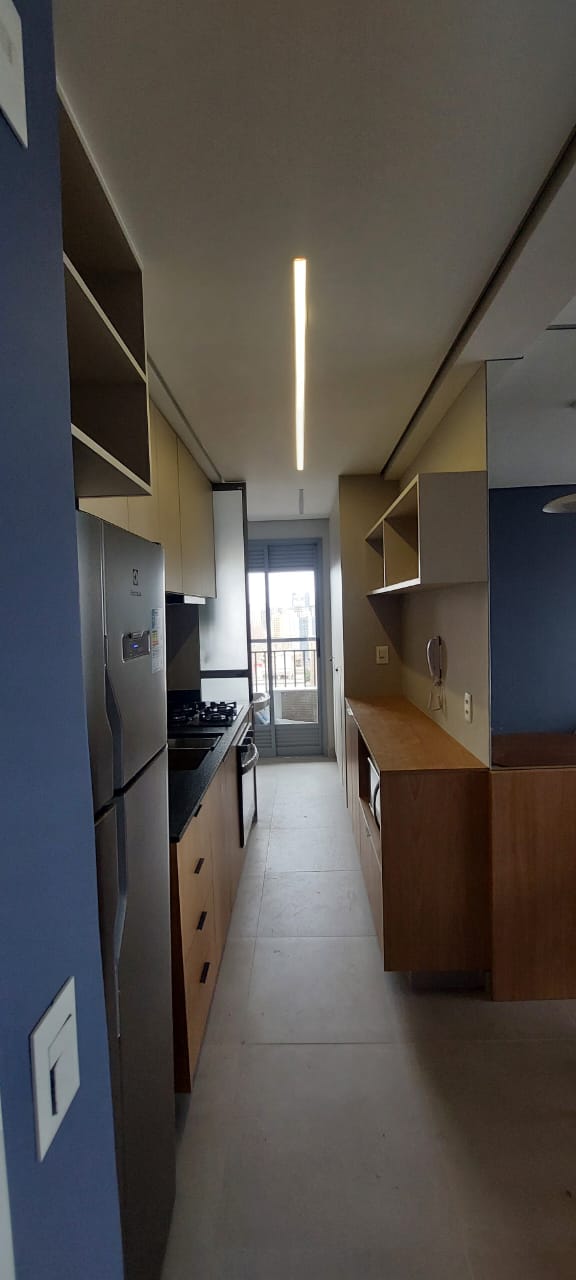 Cozinha corredor azul e madeira com LED linear e varanda ao fundo