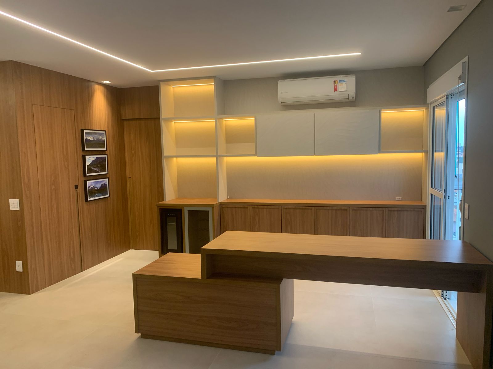Living com adega, mesa em madeira e marcenaria com iluminação LED âmbar