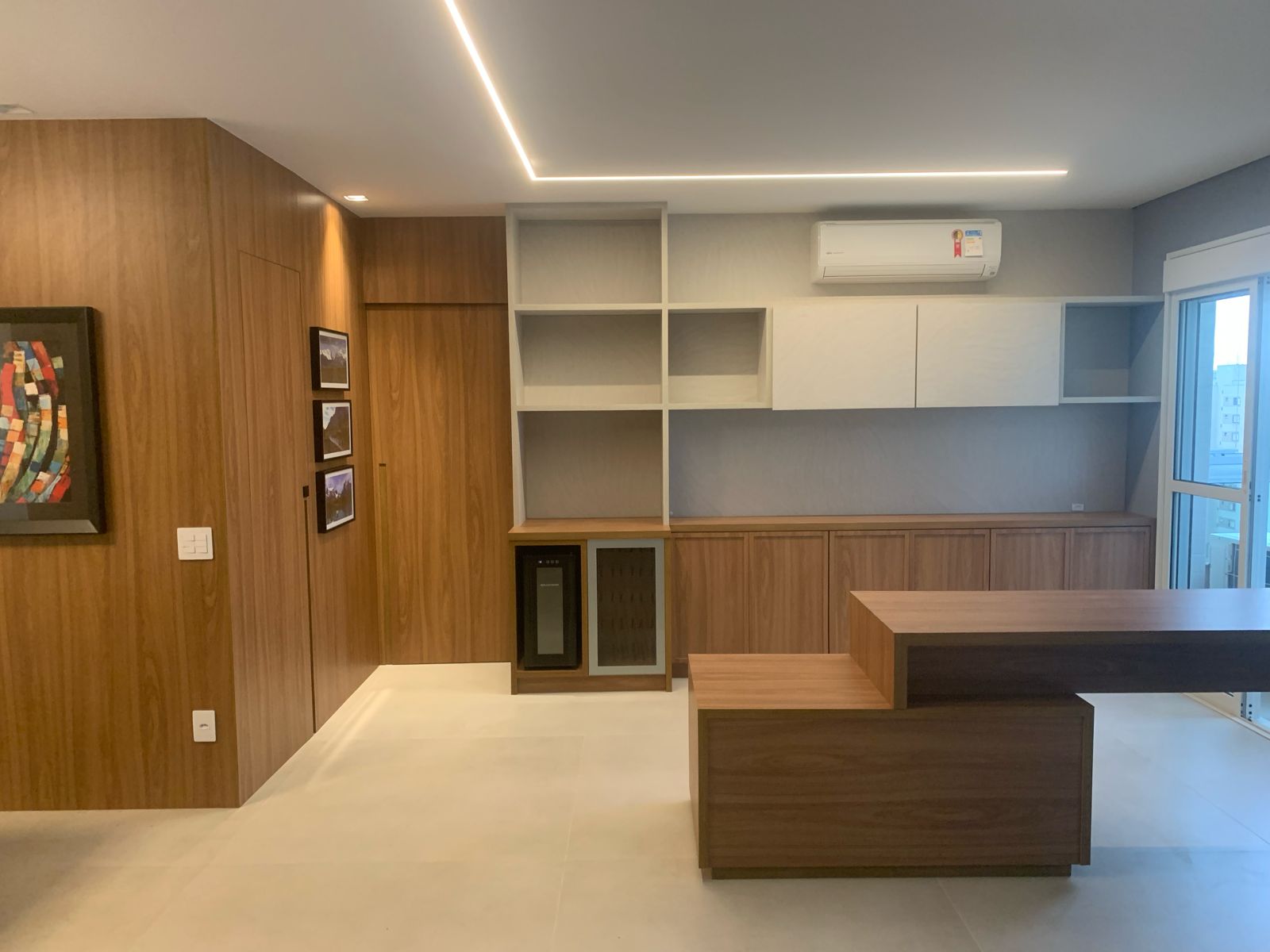 Sala de jantar integrada com adega e mesa em madeira do projeto de Carolina Brandão