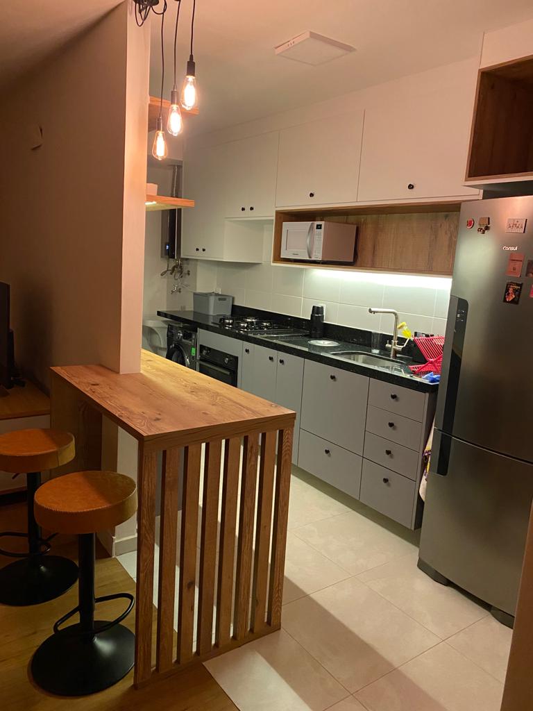 Painel ripado escuro com TV, rack cinza e cristaleira iluminada
