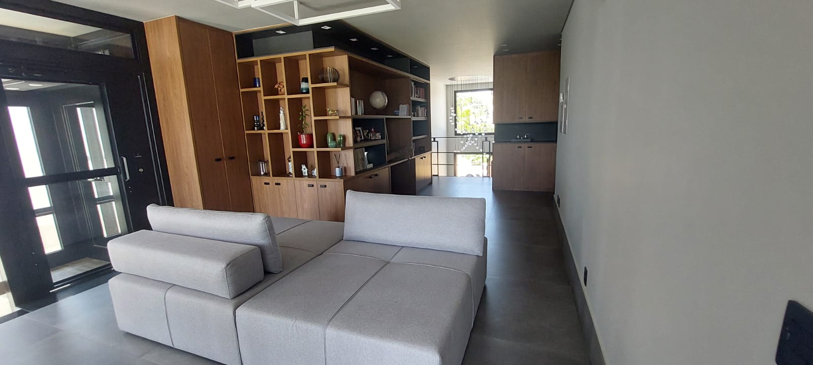 Sala com sofá modular cinza e estante de nichos em madeira e preto