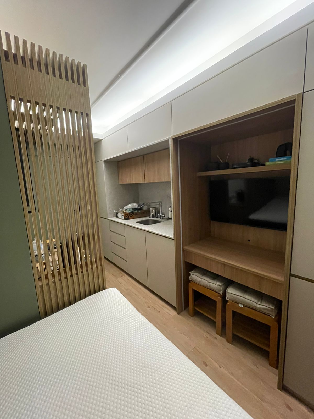 Studio compacto com kitchenette, painel de TV e divisória ripada