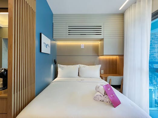 Cama de casal entre painéis com nichos iluminados e cortina