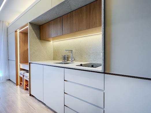 Kitchenette branca com bancada de pedra, cuba e torneira cromada